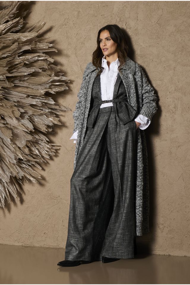 Elegante Frau in langem, glitzerndem Hosenanzug mit weißem Hemd und dunkler Jacke.