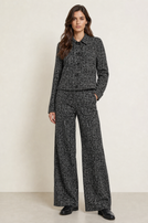 Frau trägt eleganten Tweed-Anzug mit weitem Schnitt und schwarzen Pumps.